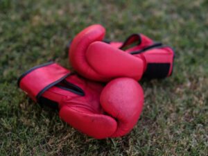 Close-up of structured leather rowing gloves with wide flat cuffs resting on a wooden surface