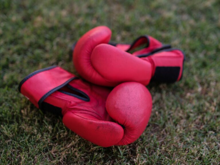 Close-up of structured leather rowing gloves with wide flat cuffs resting on a wooden surface