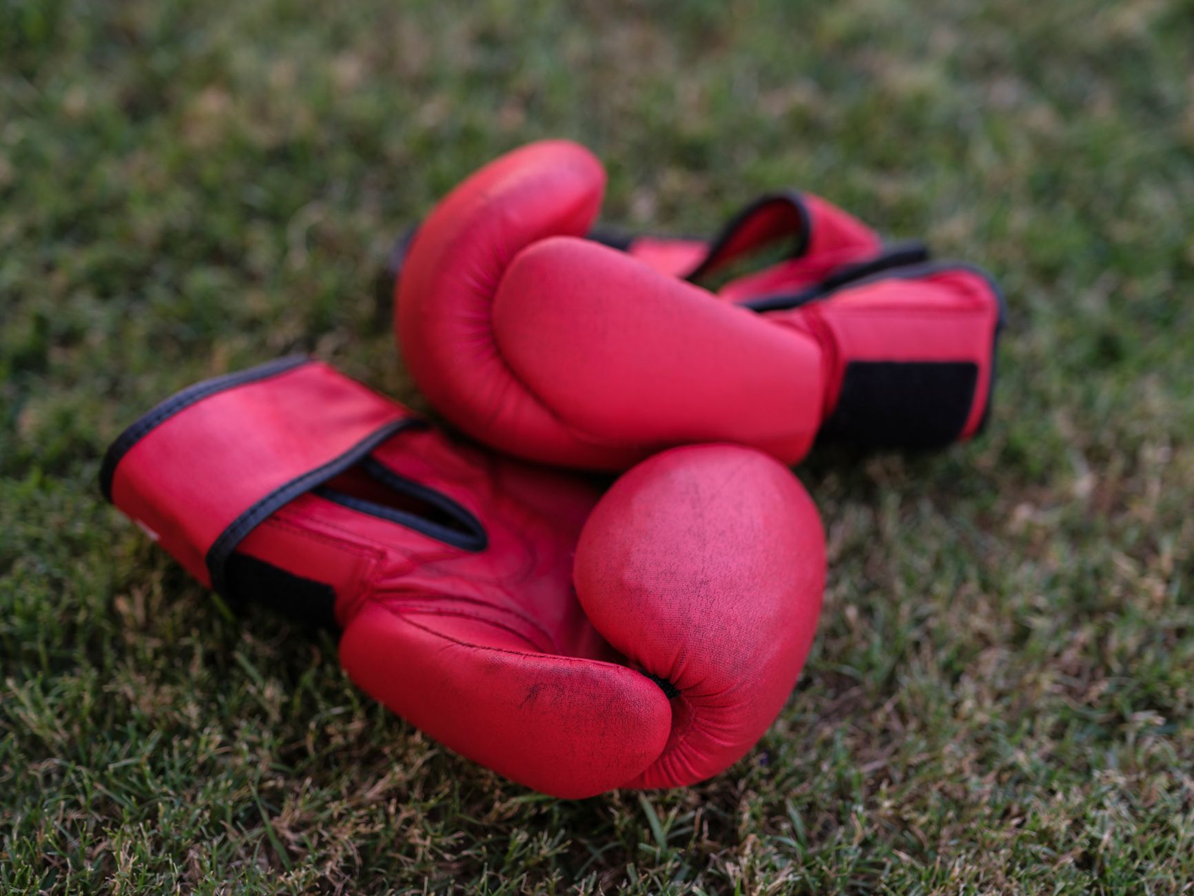 Close-up of structured leather rowing gloves with wide flat cuffs resting on a wooden surface