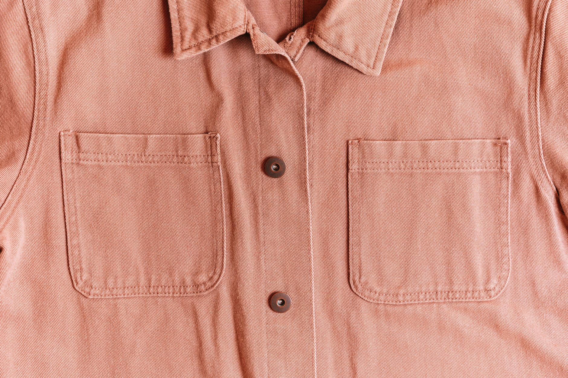 Detail shot of brass hardware studs on a shirt placket against white fabric