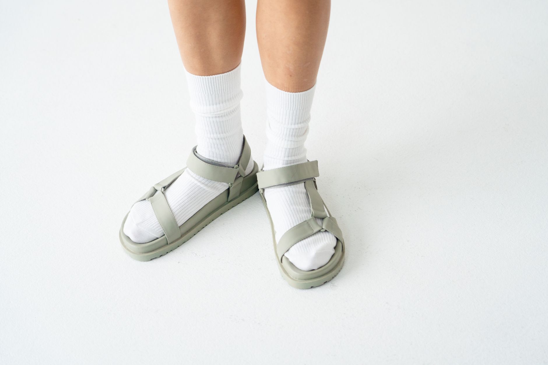 Clean minimalist leather sandal with narrow strap across the foot on a neutral background