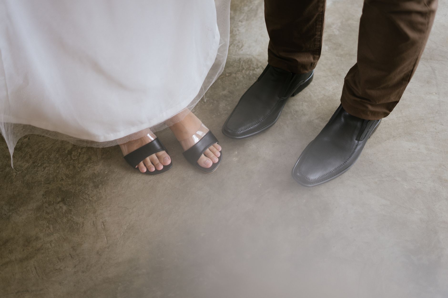 A pair of minimalist leather mules on a clean surface, showing the narrow shank profile and architectural sole edge