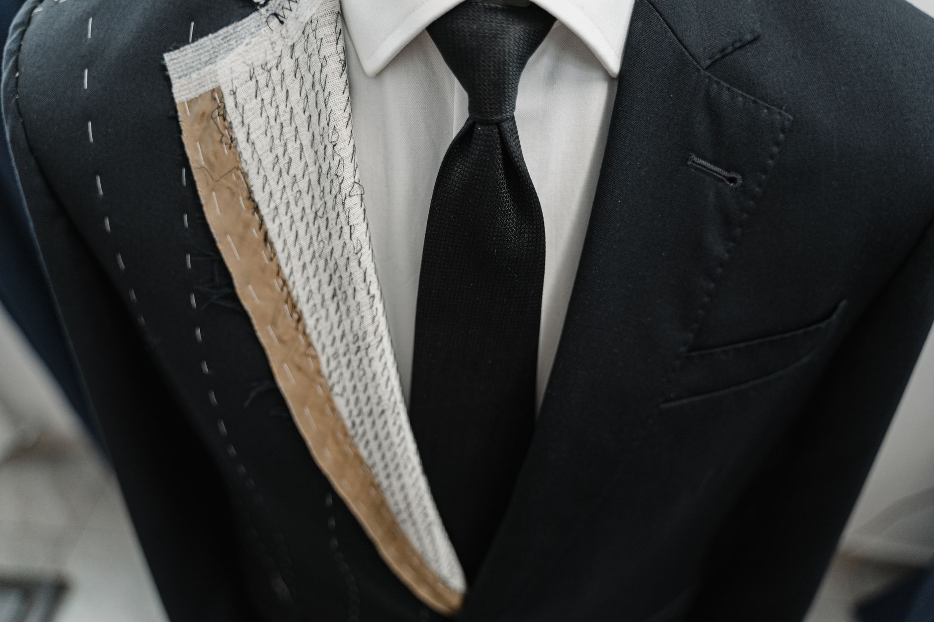 Detailed view of a structured blazer cuff with visible decorative stitching along the hem edge