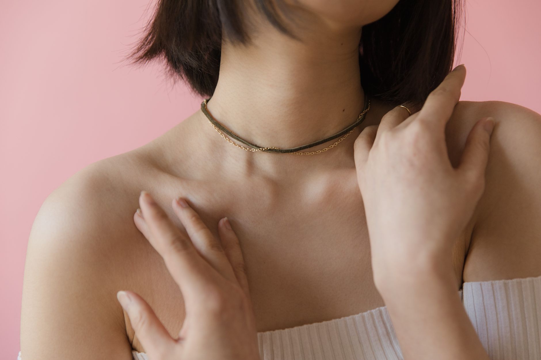 A simple leather choker with a centered metal ring worn at the throat against a neutral background