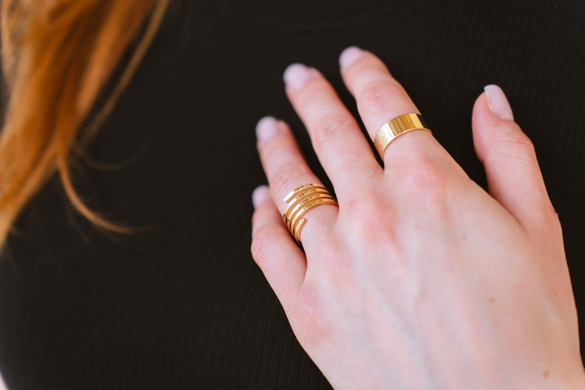 Multiple thin gold rings stacked on a finger with even spacing between each band