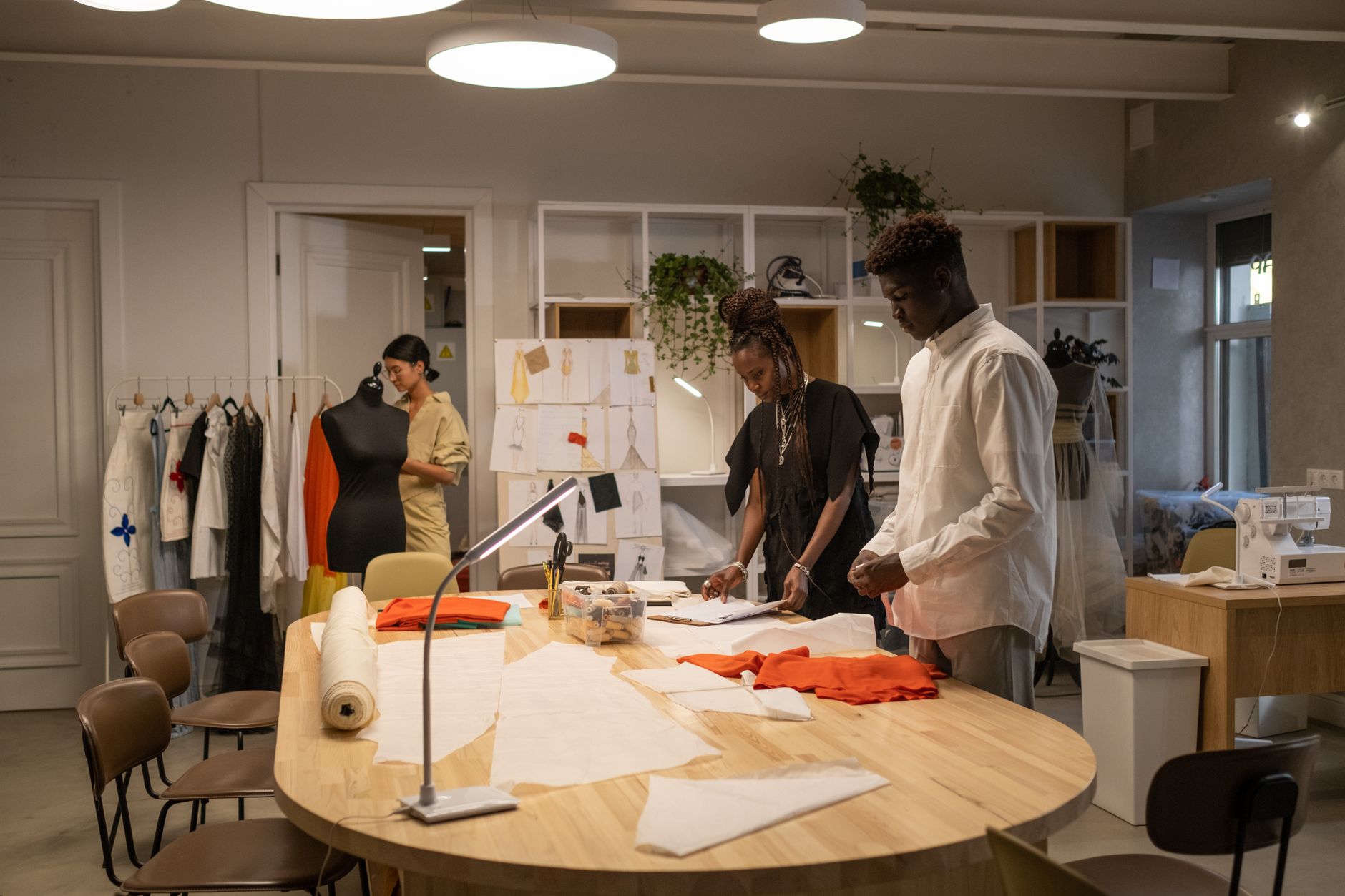 Designer working with heavy fabric panels in a fashion studio focused on structural garment construction