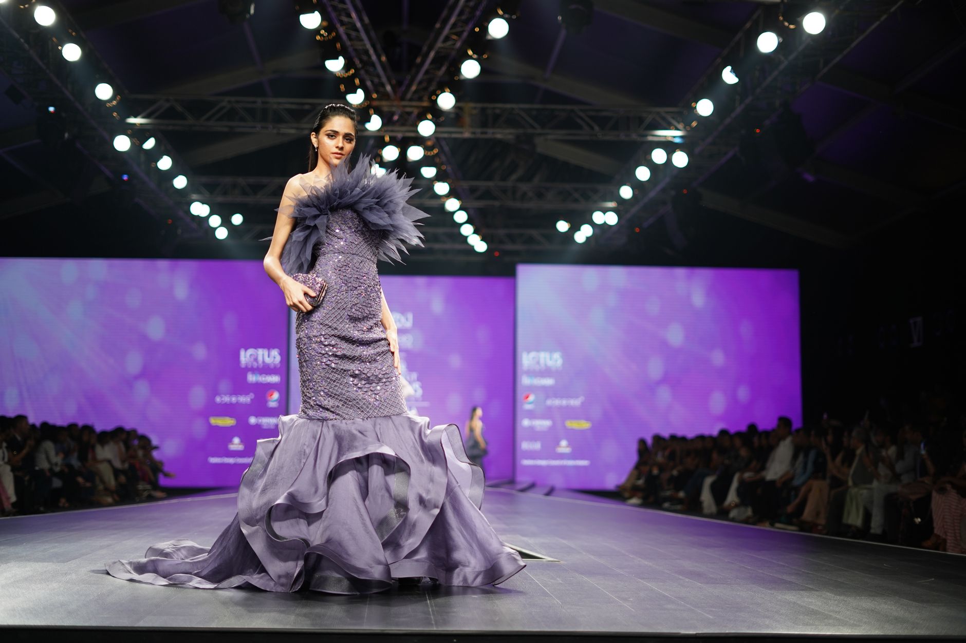 Model wearing a structured bodice garment with architectural seam detail on a fashion runway