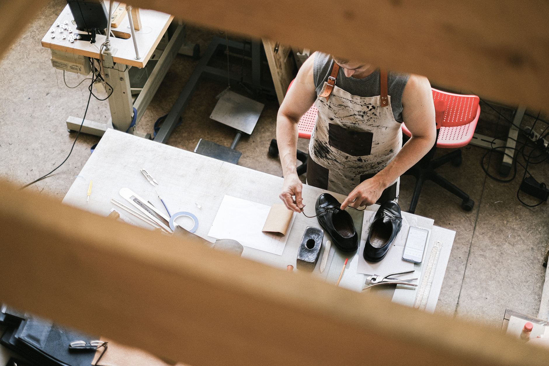 Shoemaker working on a leather strap detail at a craft workbench