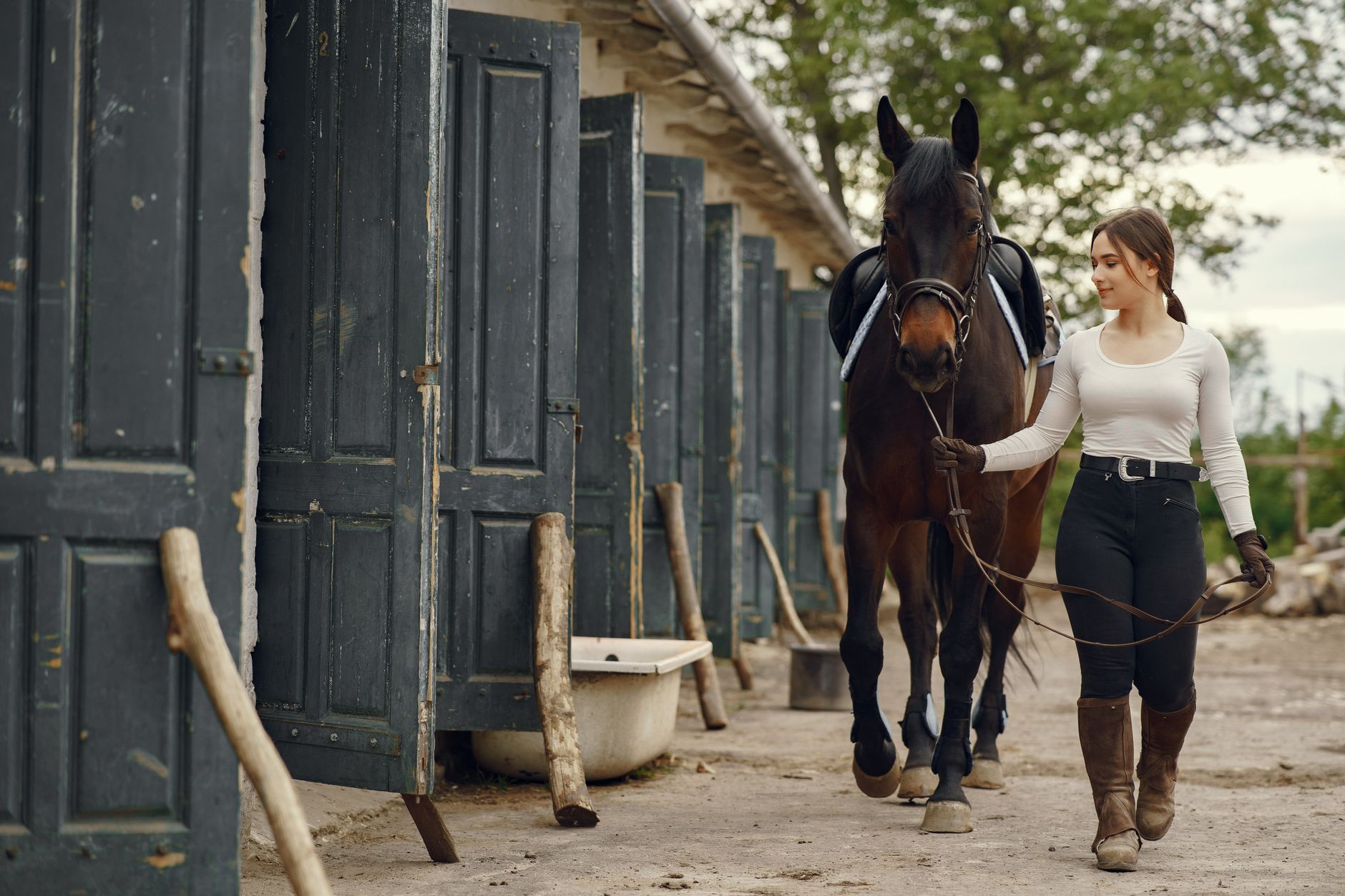 Equestrian-inspired fashion detail showing leather tab and metal buckle on tailored trousers