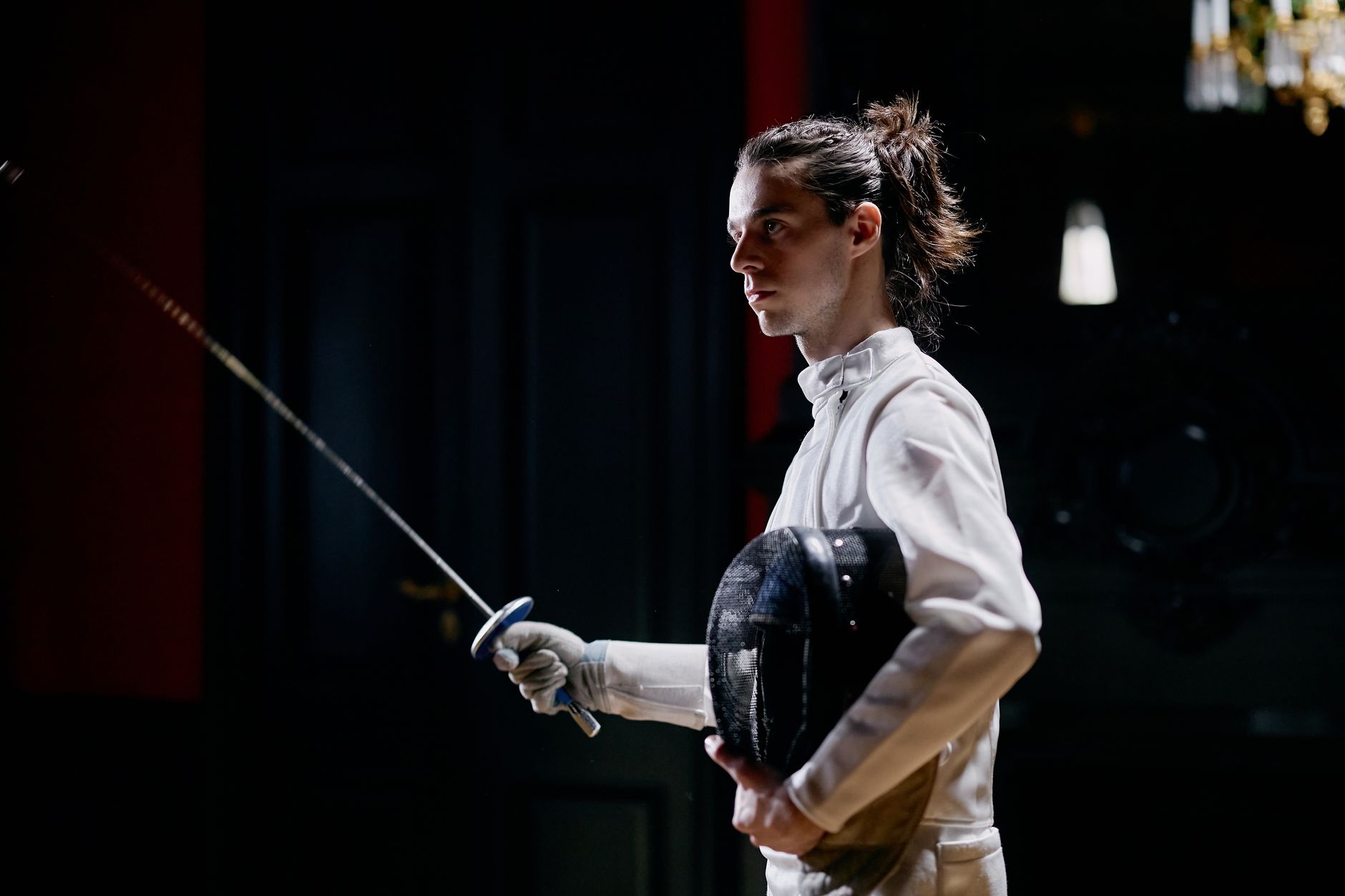 Fencer in protective breeches showing reinforced knee panel during athletic stance